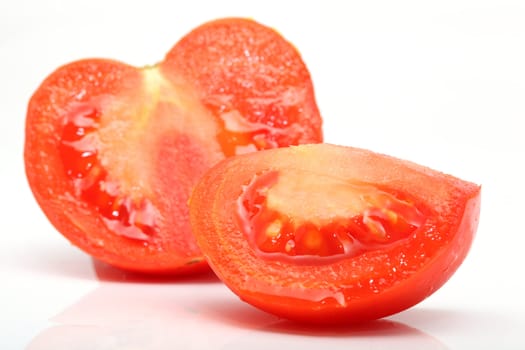 sliced juice tomato closeup isolated on white background with reflection