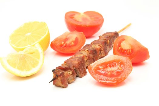 pork kebap on wooden stick grilled isolated with tomatos and lemon