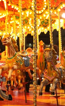 horses from colorful carousel with lights at night