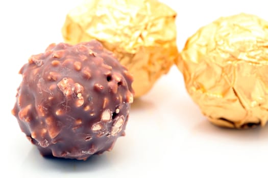 closeup chocolate sphere with nuts with gold wraped defocus background