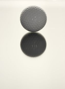 A white golf ball on a reflective surface