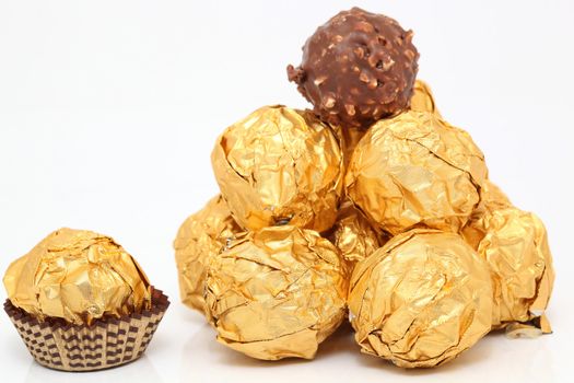 closeup gold wraped chocolate balls pyramid isolated on white background