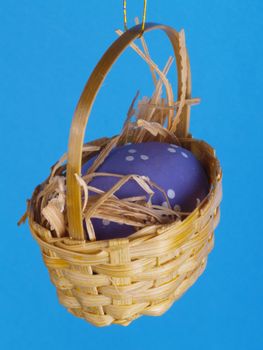 easter decoration miniature basket with egg over blue