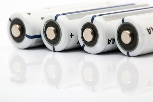 four white alkaline batteries on white background with reflection