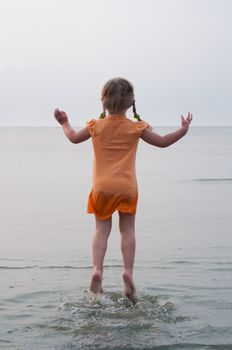 Little girl jumping on the sea, nature