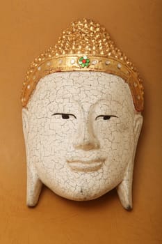 handcrafted wooden buddha face decorative mask on yellow background 