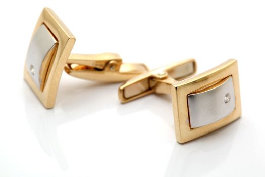 Pair of gold cuff links with diamond isolated with reflection