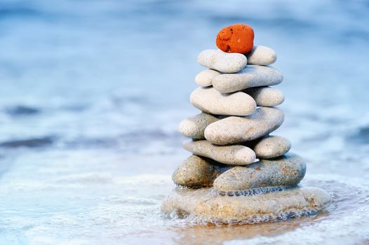 Pile of a sea pebble with a red stone about a mark