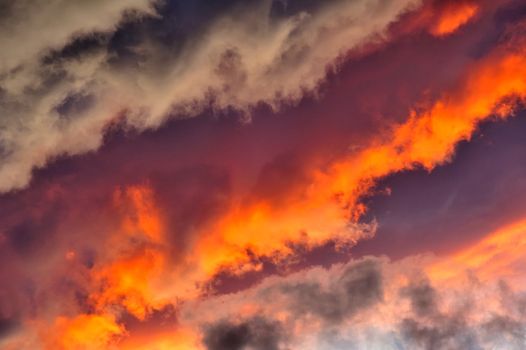 A jumble of stratocumulus clouds at sunset arranged in lines with a diagonal composition. Suitable as an abstract, natural graphics background.