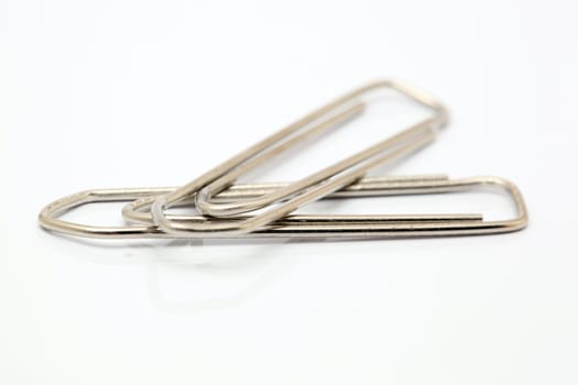 closeup two metallic paper clips isolated on white background