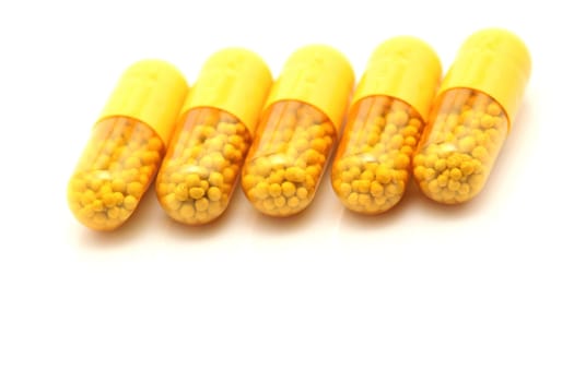 yellow medical capsules closeup detail with reflection on white background