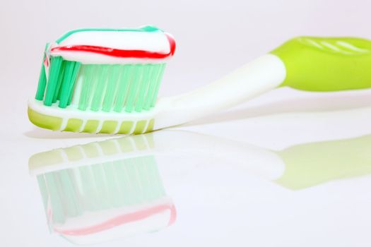 tooth paste on green brush closeup with beautiful reflection on white