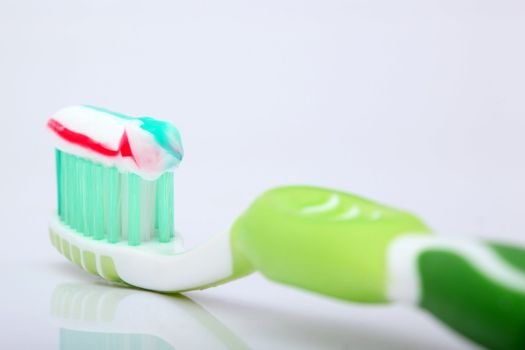 tooth paste on green brush closeup with beautiful reflection on white