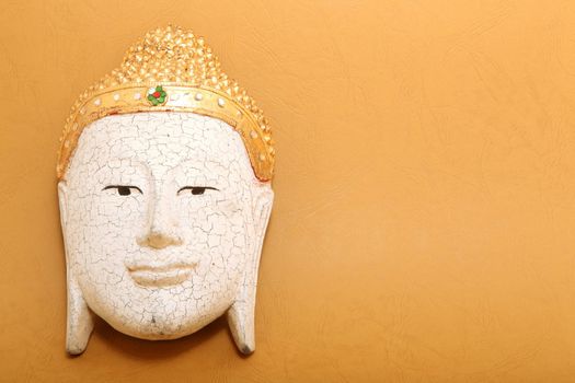 handcrafted wooden buddha decorative mask on yellow background with copyspace