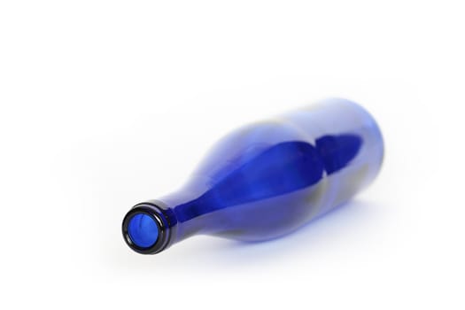 Blue glass empty bottle lying on white background