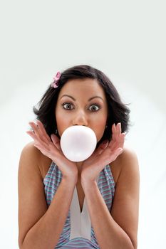 Beautiful Latina girl with huge eyes open blowing a bubblegum bubble, isolated