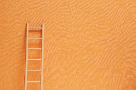 Conceptual background with wooden ladder against ginger wall