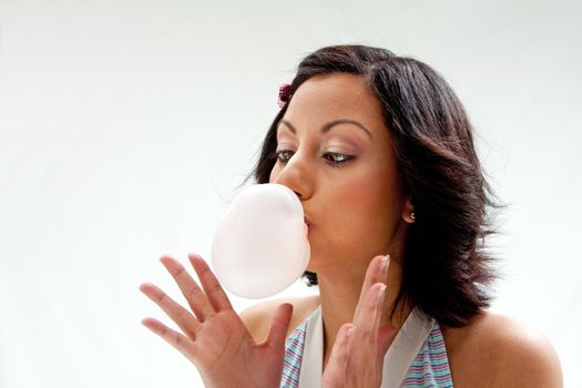 Beautiful Latina girl with crossed eyes blowing a bubblegum bubble, isolated