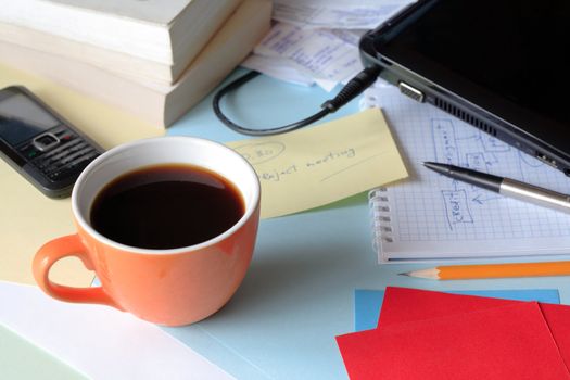 Cup of black coffee standing on a table near laptop and paper