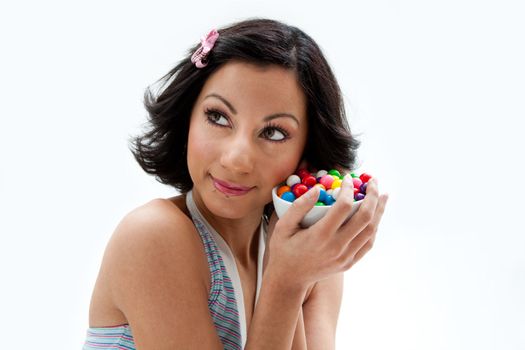 Happy beautiful candy girl with a bowl of colorful bubblegum candy balls next to her cheek, isolated