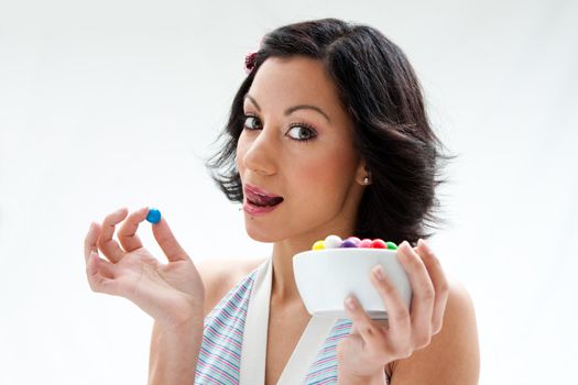 Happy beautiful candy girl with a bowl of colorful bubblegum candy balls licking her lip, isolated