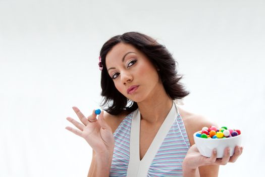 Happy beautiful candy girl with a bowl of colorful bubblegum candy balls thinking, isolated