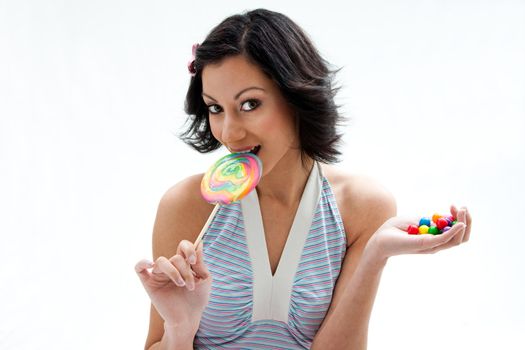 Happy beautiful candy girl with a hand full of colorful bubblegum candy balls licking a lollipop, isolated