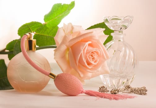 Two small bottles and soft pink rose with green leaves
