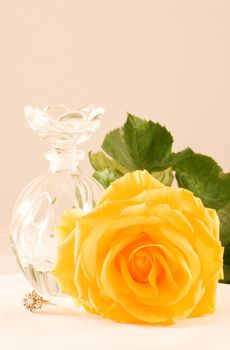 Yellow rose with green leaves, small glass bottle and diamond ring