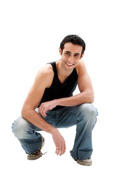 Handsome smiling Caucasian guy wearing black tank top and jeans squatting, isolated