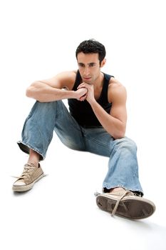 Handsome Caucasian guy wearing black tank top and jeans sitting on floor thinking, isolated