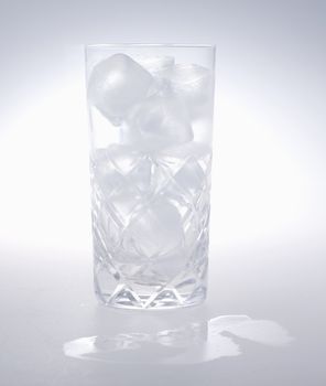 Close up of glass full of ice cubes over white