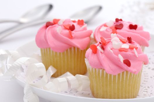 Small pink cupcakes decorated with heart candies to celebrate Valentine day