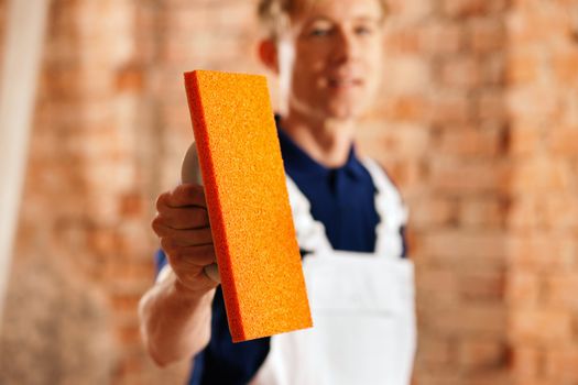 Bricklayer with trowel at a construction site, focus is on the trowel!