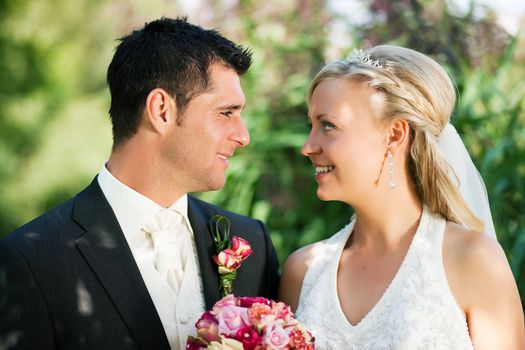 wedding couple looking at the viewer, the bride holding a bouquet of flowers in her hand