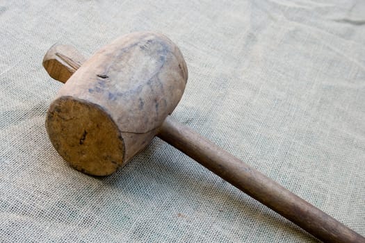 Old wooden mallet hammer on burlap background