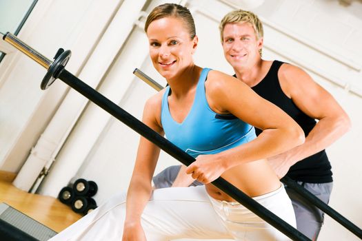 Very attractive and sportive couple doing power gymnastics with barbells