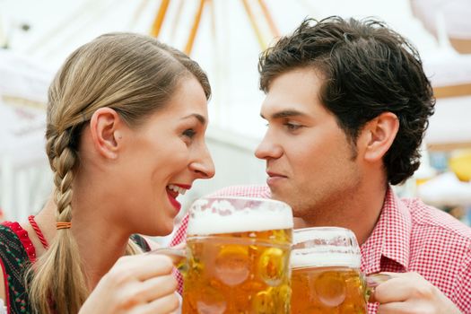 Couple in traditional German costume in a beer tent having a drink, scene could be located at the Oktoberfest or any Duld