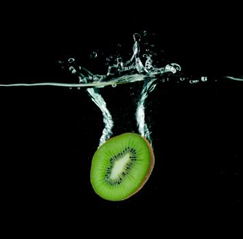 kiwi falling into water, isolated on black