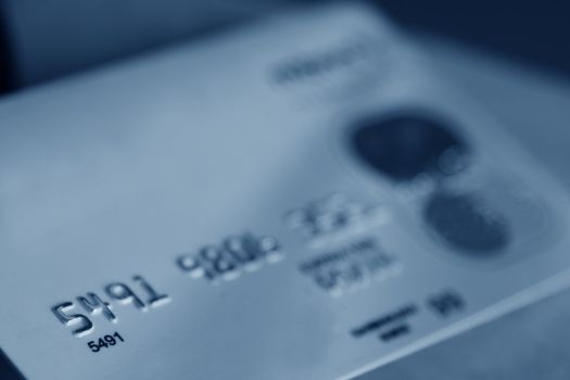 A close-up of a credit card, cast in blue.
