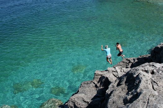 Two girls jumping off the cliffs at Cypress Lake National Park, in Ontario, Canada.