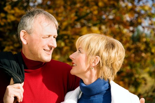 Mature couple deeply in love on a fall day having a walk holding each other tight