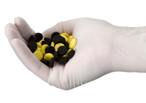 Yellow and black tablets on hand in surgeon's glove