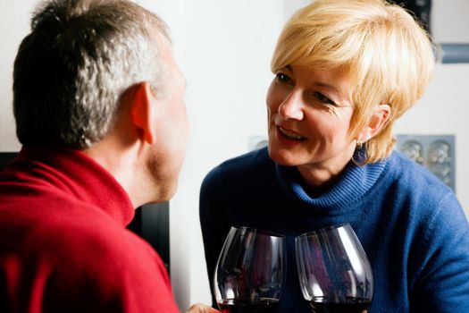 Mature couple having fun clinking glasses with red wine in a romantic setting