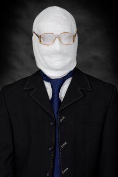 Businessman - mummy in spectacles on the black background