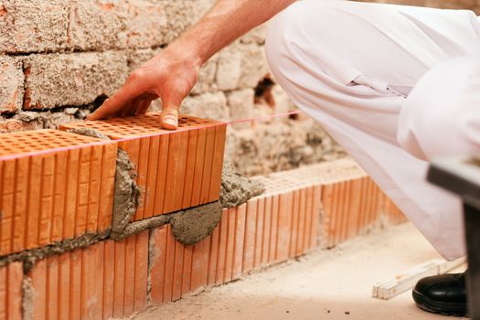Bricklayer with brick at a construction site, focus on brick