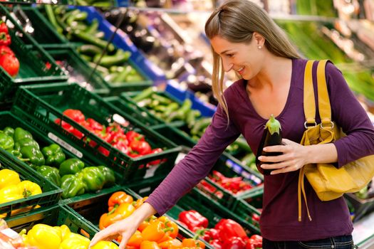 woman in a supermarket at the vegetable shelf shopping for groceries, she is choosing