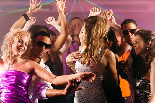 Group of friends - men and women of different ethnicity - having fun in a disco or nightclub