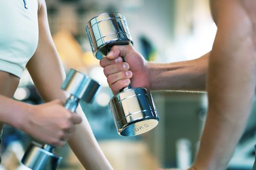 Two people (male / female) lifting dumbbells, shallow depth of field