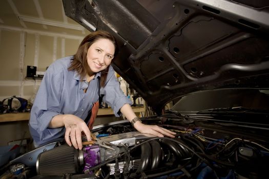 Female Hispanic mechanic working on a car engine